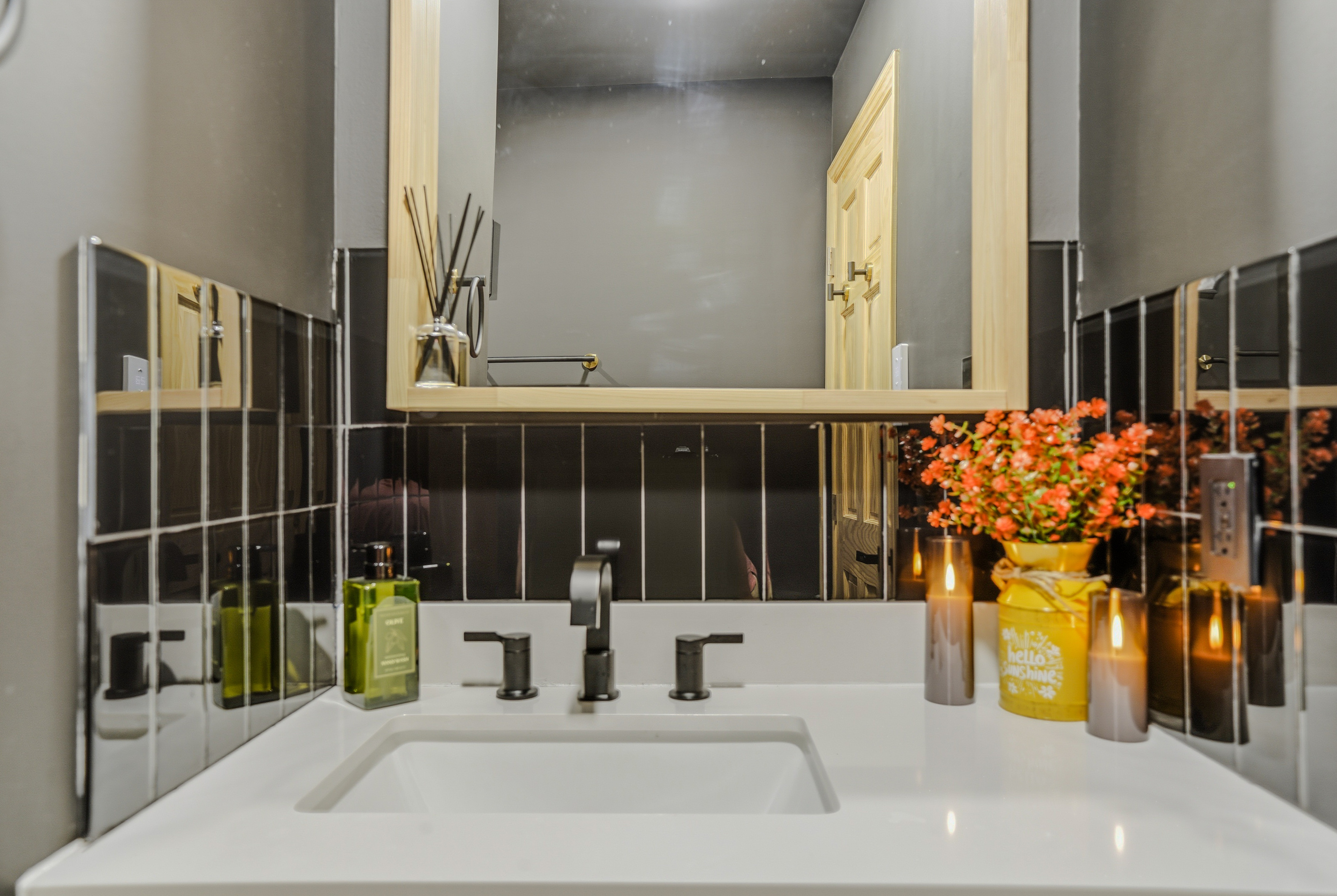Primary bathroom vanity — double sinks, gold fixtures, dark tile, and ambient lighting