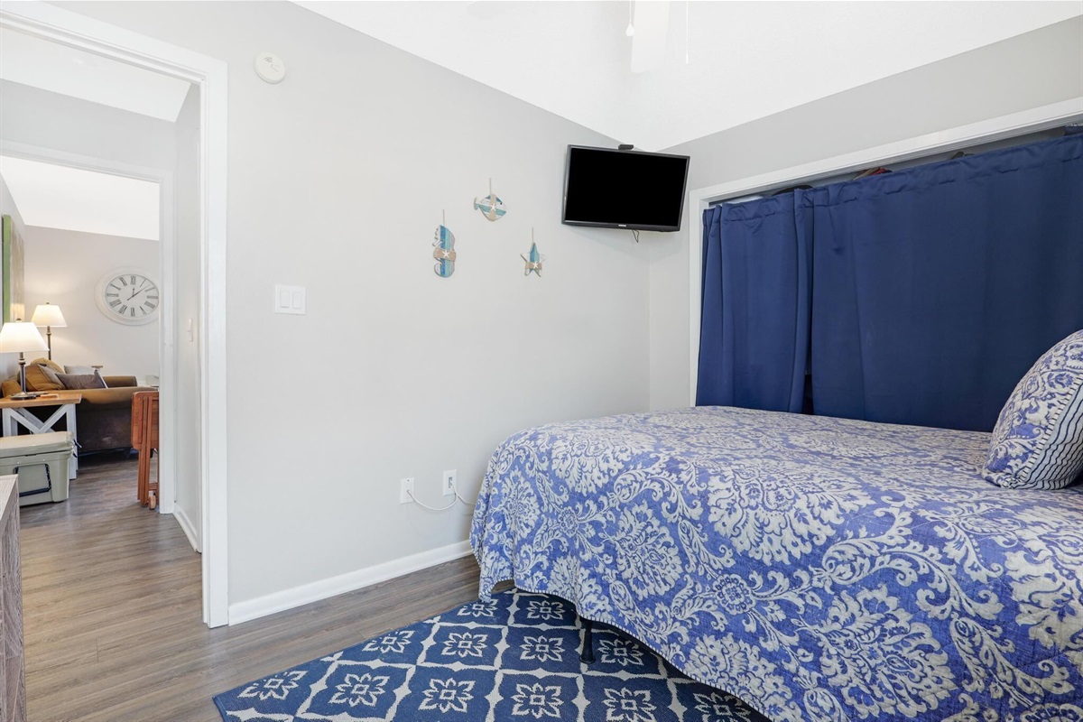 Bedroom - The spacious bedroom features Queen bedding, mounted television, and balcony access.