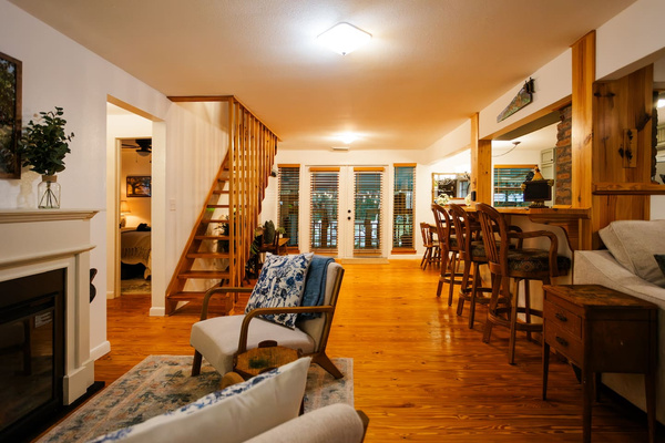 Open concept living, anchored by the fireplace and a pine stairway to the loft.
