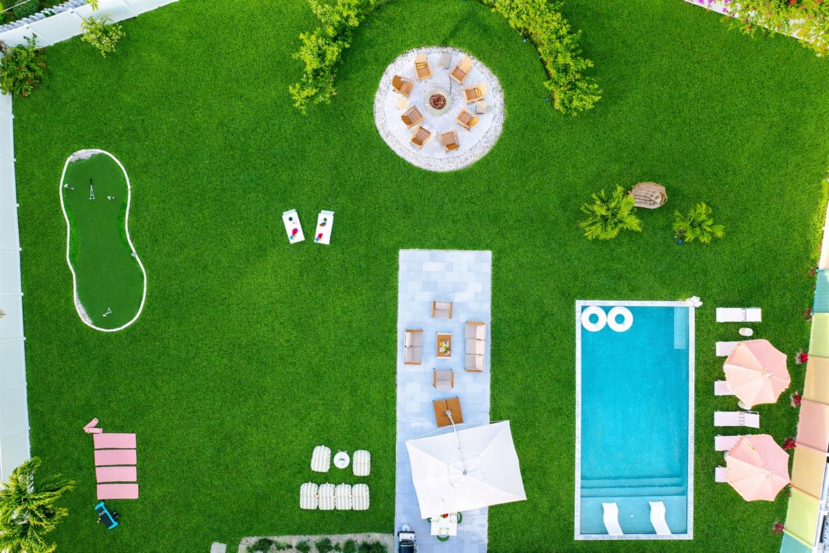 Private Palm Beach backyard with heated saltwater pool, fire pit, mini golf putting green, and outdoor lounge seating.