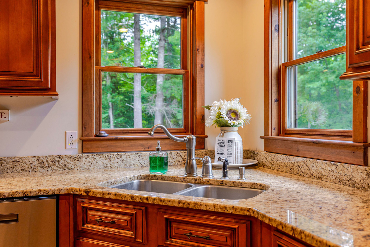Prepare meals with ease in the fully equipped kitchen, where granite countertops, rich wood cabinetry, and peaceful forest views make cooking a pleasure.