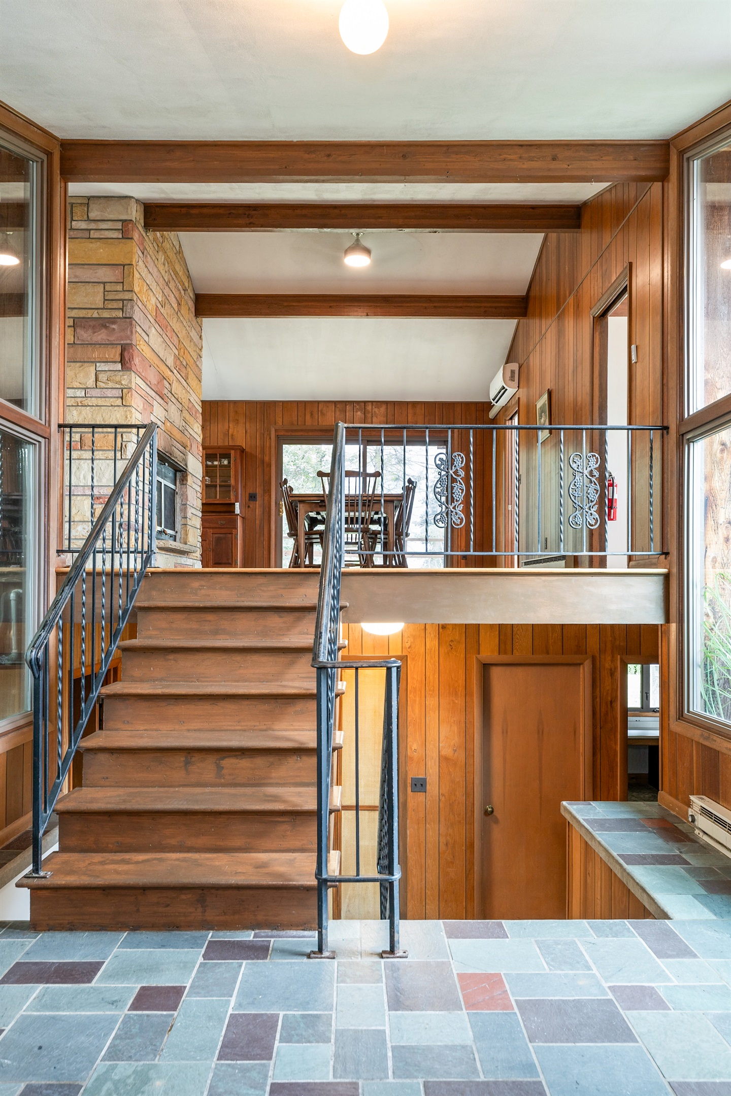 Step into warmth with soaring windows, wood-paneled walls, and a charming stone fireplace that welcomes you into this inviting retreat.