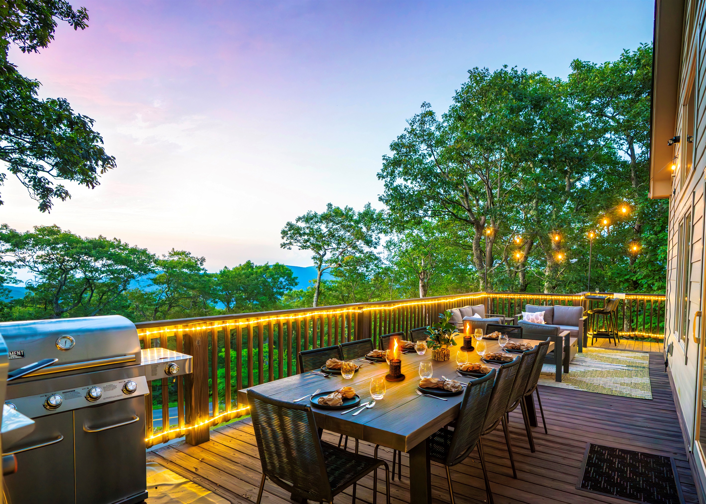 Twilight on the deck — mountains fading in the distance, wine glasses catching the glow of string lights, dinner sizzling on the grill. This is what gathering should feel like
