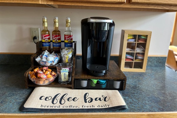 Coffee bar includes Keurig coffee maker, syrups, creamers, sugar, and sugar alternatives.
