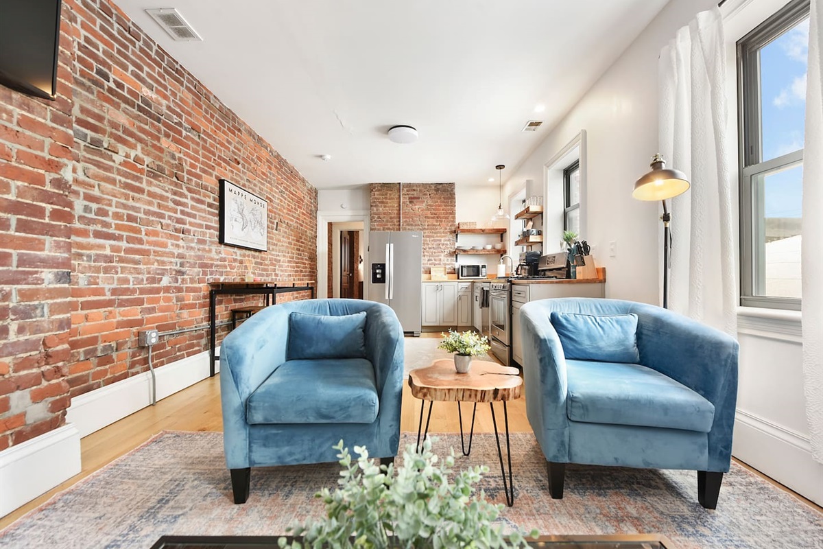 Sink into the plush L-shaped sofa and enjoy the inviting ambiance of this elegant living room, complete with a stylish rug, chic décor, and a stunning TV setup.
