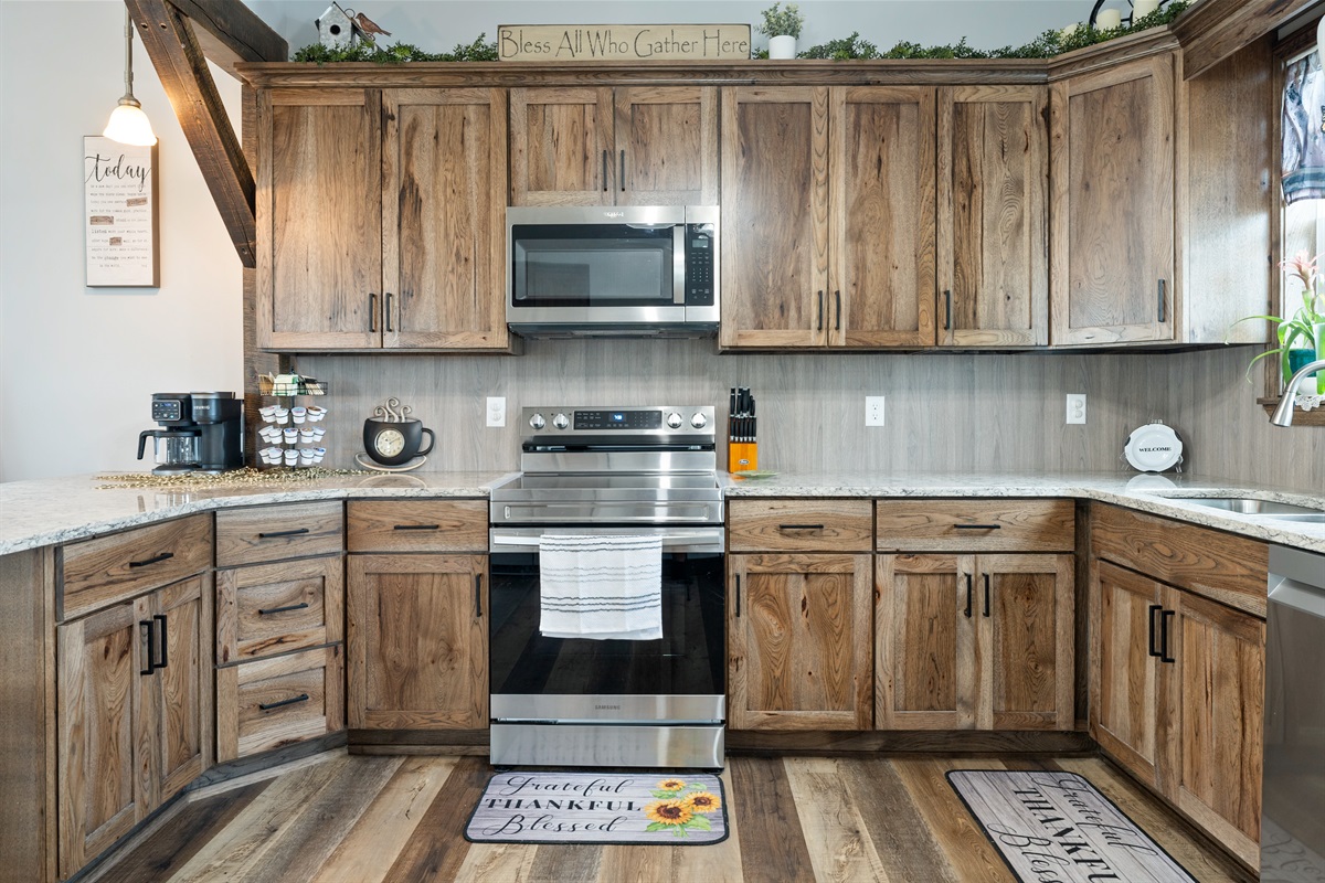 Beautiful farmhouse-style kitchen with warm wood cabinetry, granite counters, and a spacious island with bar seating for four.