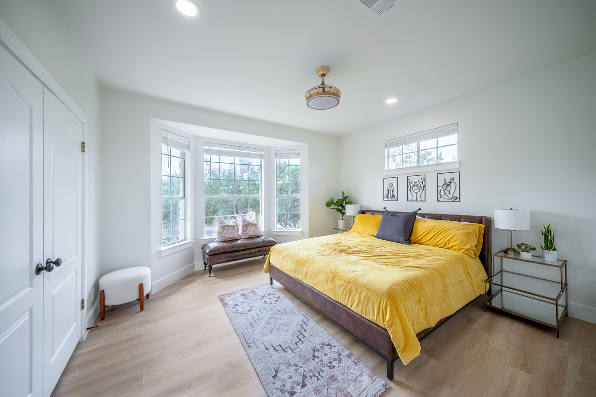 Sunlit King bedroom with a cheerful yellow accent and bay window views