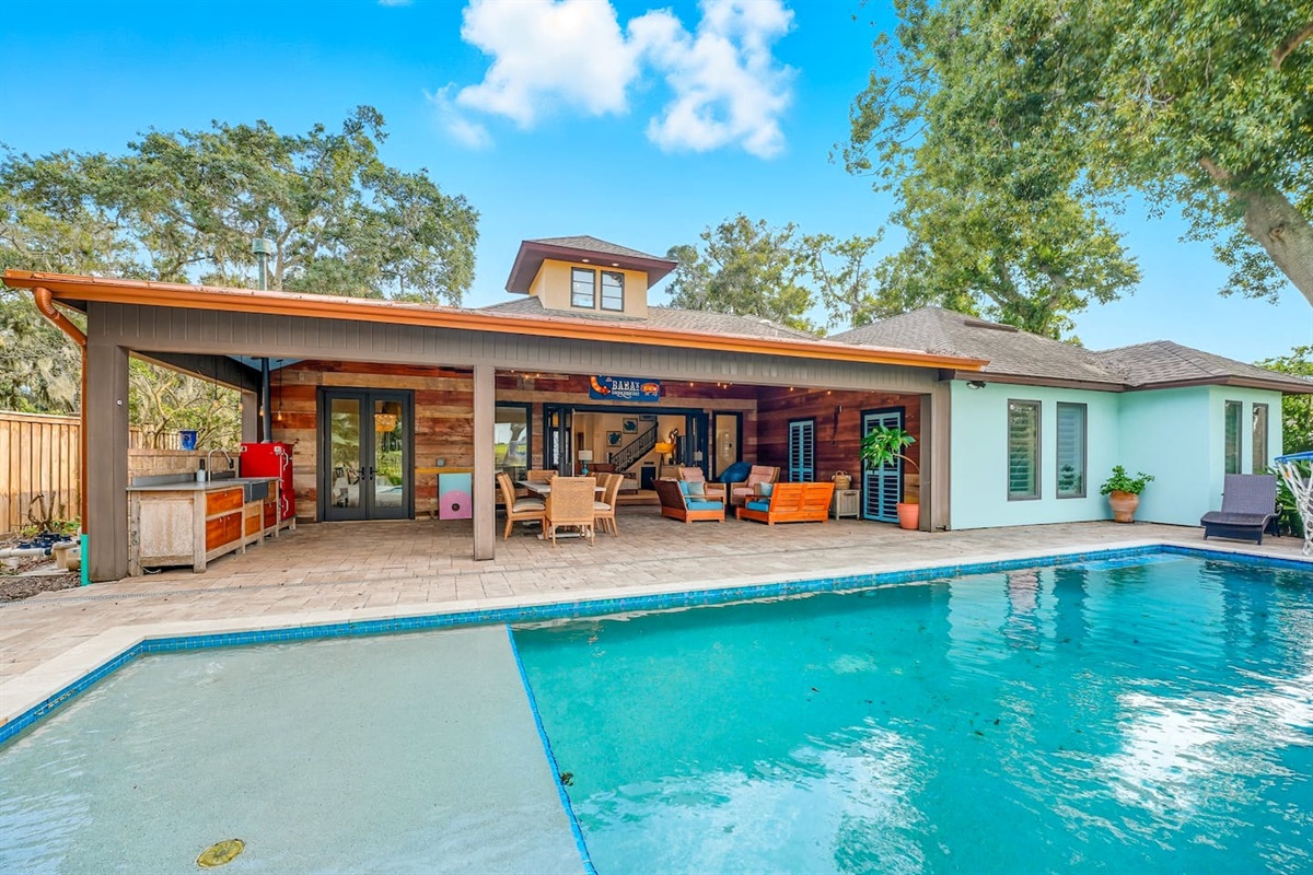 Poolside covered patio with dining, bar setup, and cornhole.