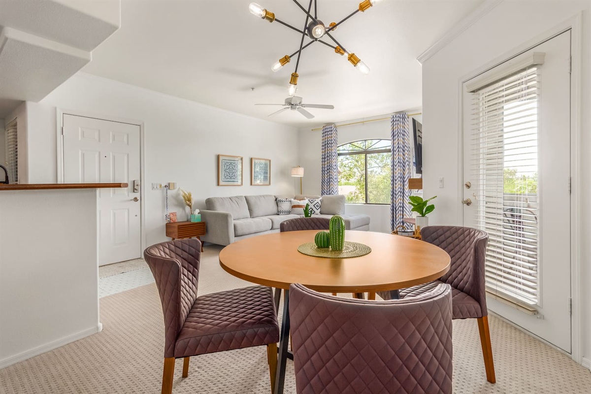 Dining space with a round table, comfortable chairs, and a connected living room layout.