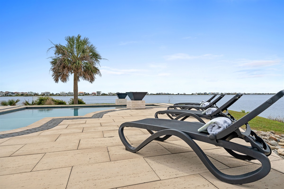 Relax poolside on lounge chairs while soaking in peaceful waterfront scenery
