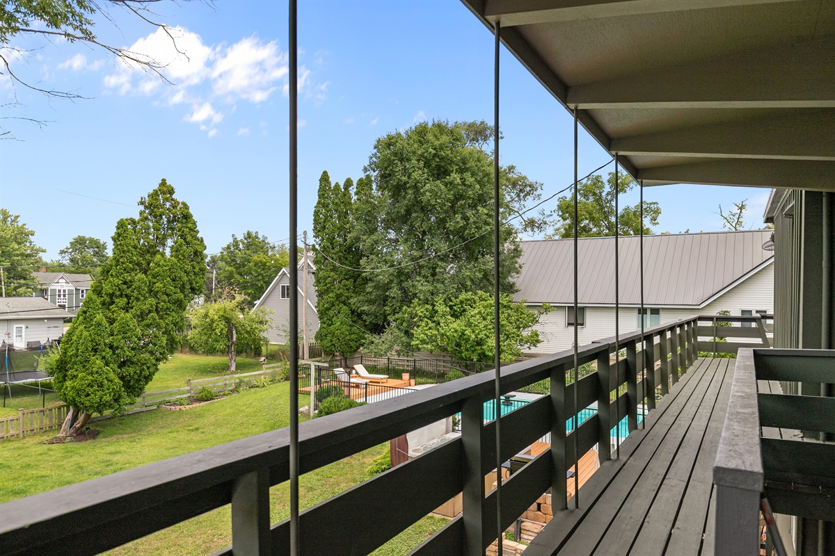 From the upper deck, enjoy a bird’s-eye view of the backyard, a perfect vantage point to take in the pool, lounge areas, and peaceful setting.