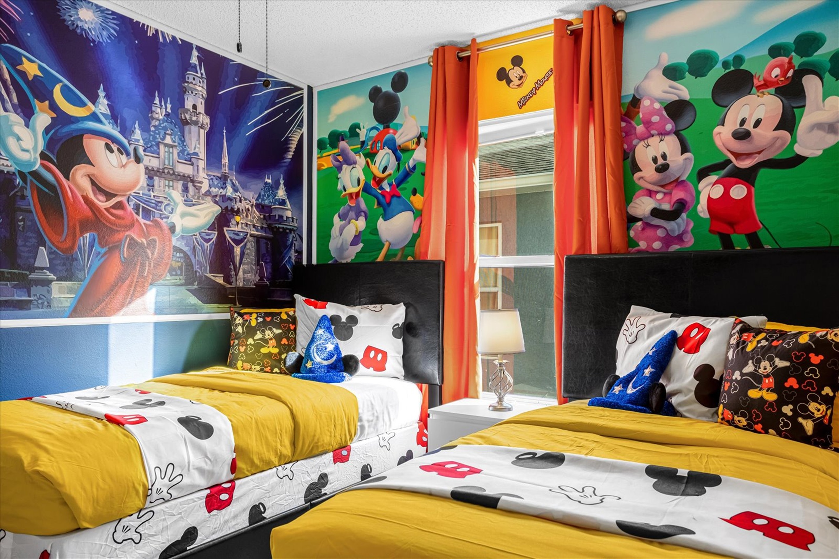 Colorful  kids' bedroom featuring twin beds with Mickey Mouse-themed bedding and wall murals.