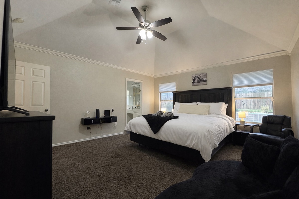 Bright master suite overlooking the backyard pool, featuring a cozy seating area that converts into a full sleeper bed.