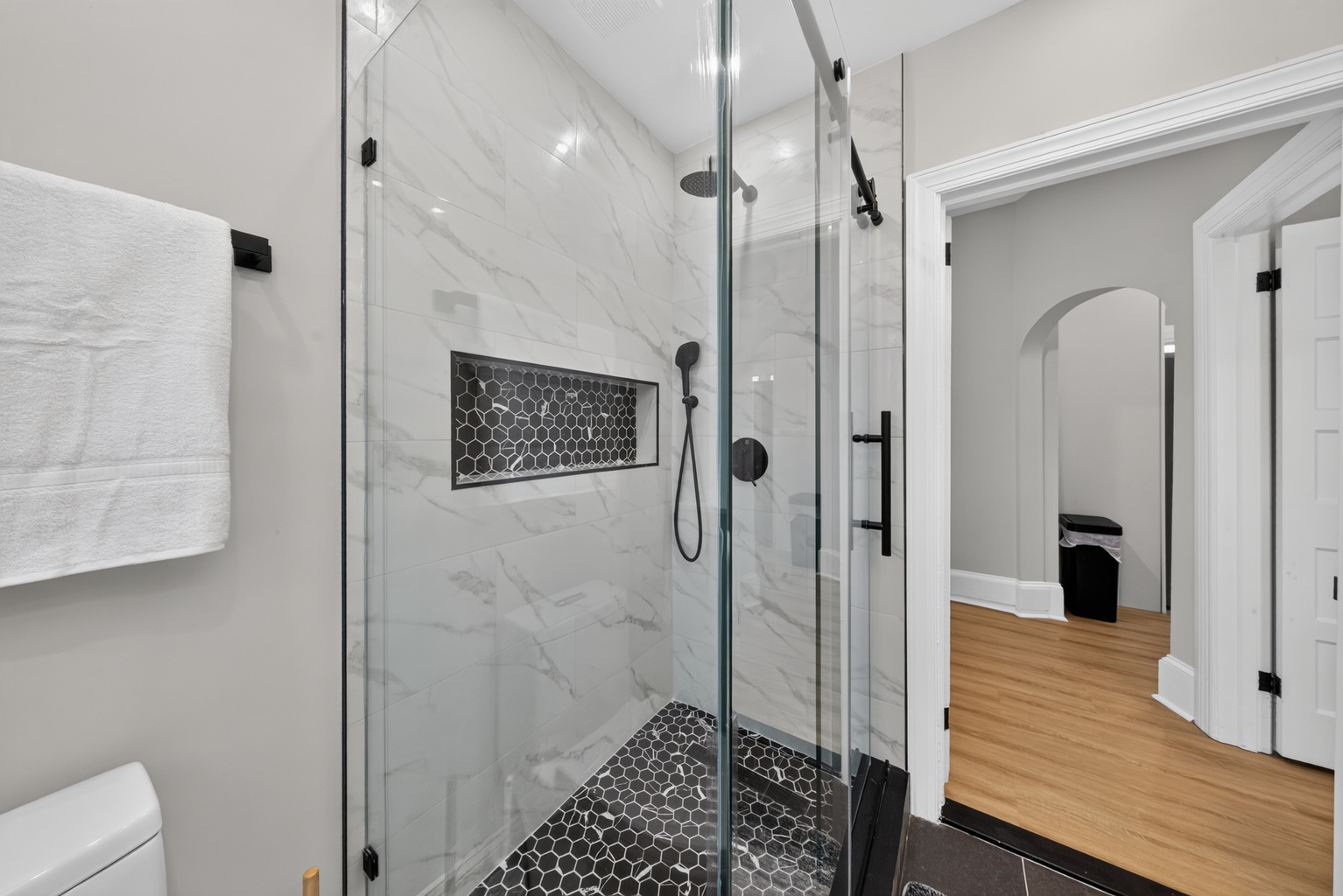 Spa-inspired walk-in shower with frameless sliding glass door, natural river stone floor, and rain showerhead.