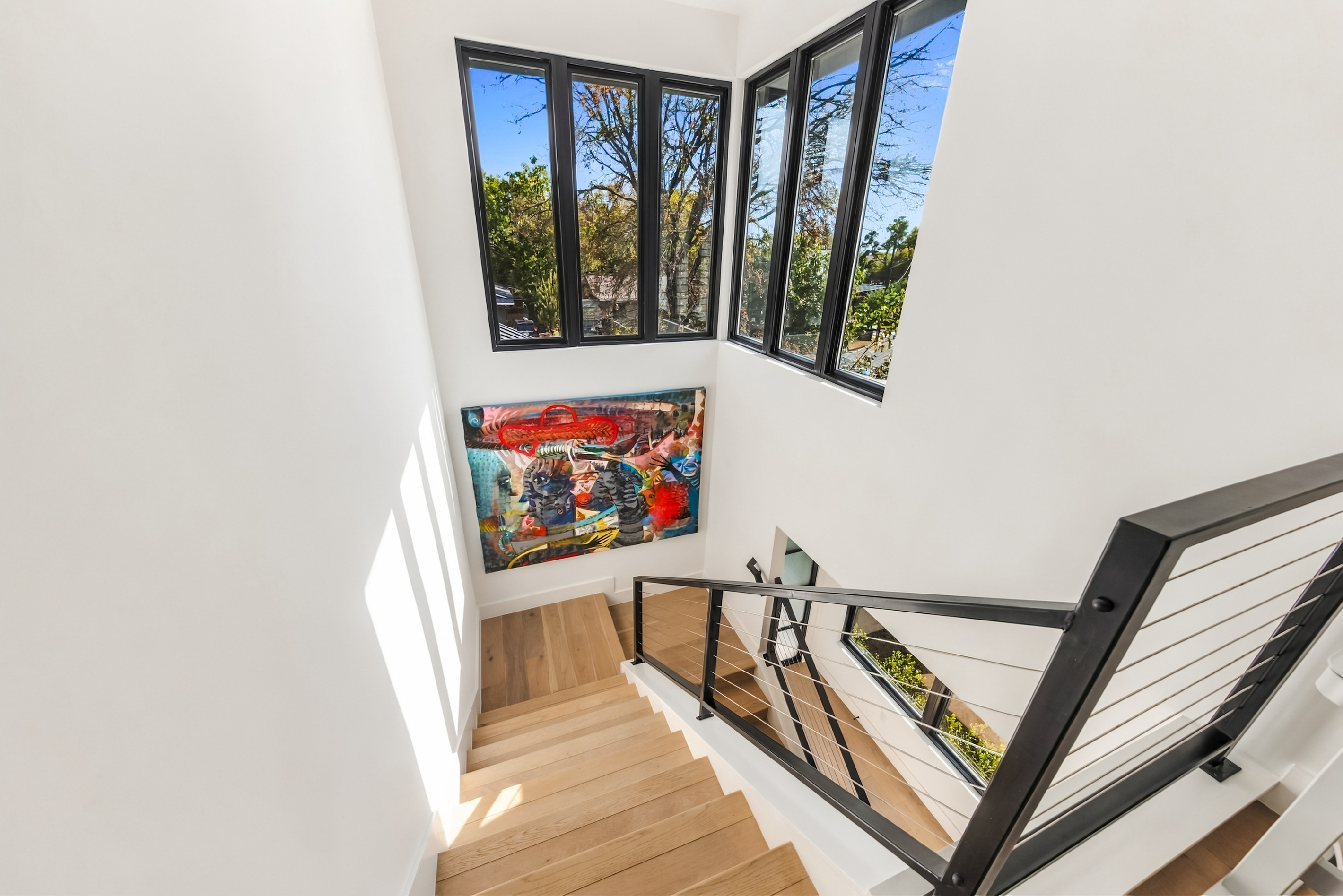 Bright stairwell framed by oversized windows and bold, colorful artwork
