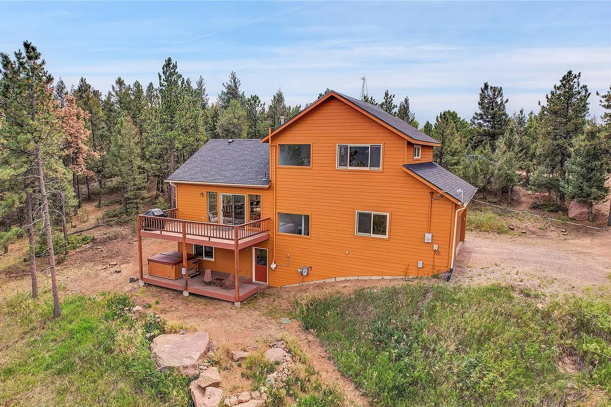 Rear exterior view highlighting the spacious multi-level deck and mountain backdrop.