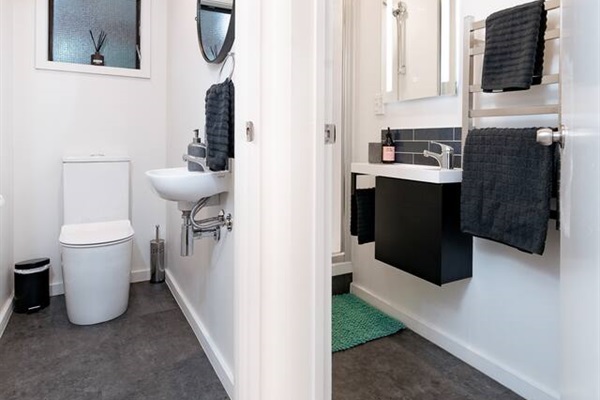 The downstairs bathroom area includes a separate toilet, shower, vanity and heated towel rail, giving guests more flexibility across the apartment.