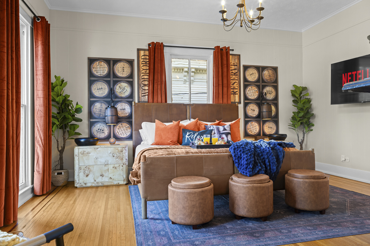 The Woodford Reserve Room features a king bed, elegant chandelier, bourbon barrel art panels throughout, and a TV above the fireplace with Netflix ready to stream.