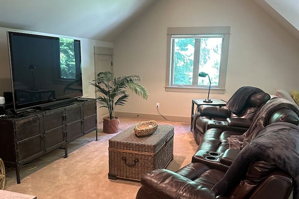 The entertainment room features leather-style recliners that seat six, perfect for movie nights on the large screen smart TV.