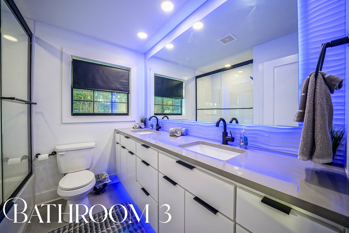 A sleek double vanity, glowing accent lights, and spa-like finishes bring high-end hotel vibes to your private stay.