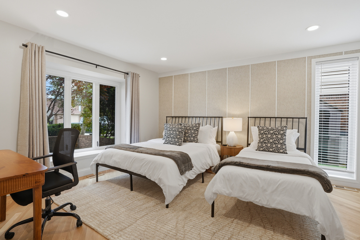 Bright, spacious bedroom with two comfortable beds, modern neutral décor, and large windows bringing in natural light. Clean, relaxing space perfect for families or group stays.