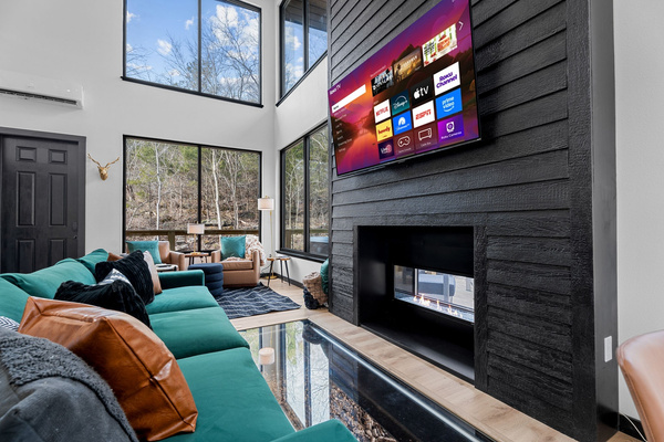Unwind by the fireplace while the creek flows below and view the surrounding forest with panoramic glass walls overlooking the private property behind the cabin.