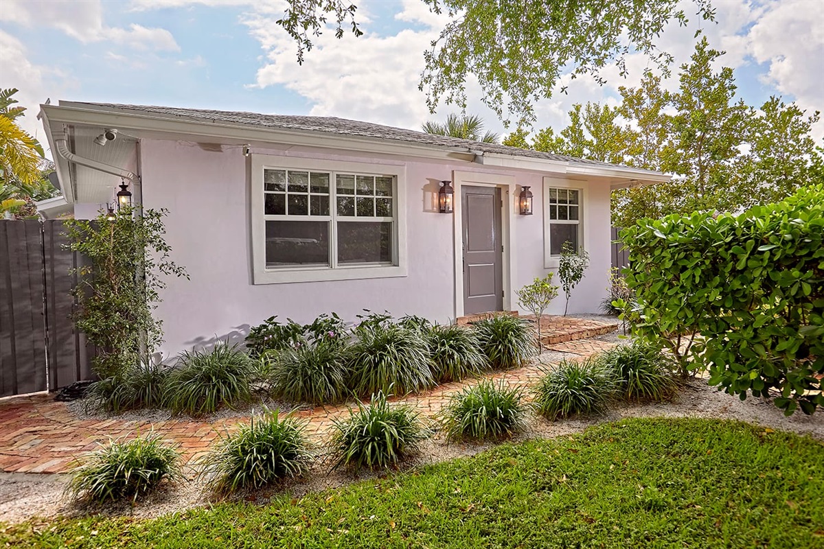 This is a charming traditional Florida home, accented with elegant copper lanterns and surrounded by lush tropical landscaping and flowering vines, with classic Chicago brick walkways for added character and appeal.
