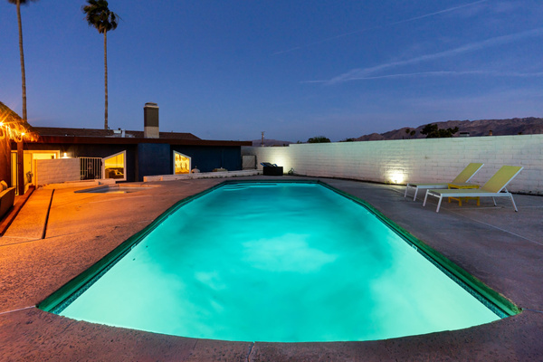 Private pool lit at night under dark desert skies