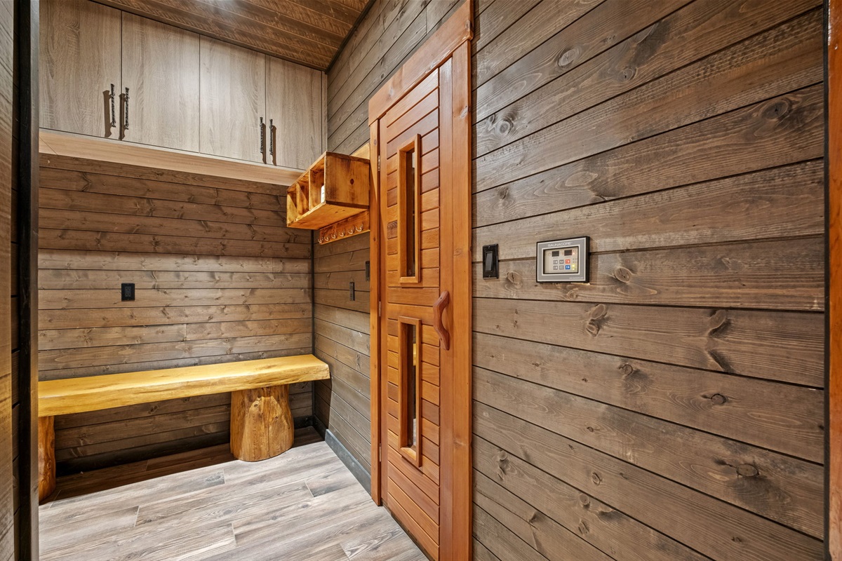 Sauna changing area with handcrafted wood bench, storage cubbies, and digital temperature controls.