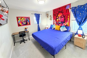 Another king bedroom offers eye-catching artwork, a wall mounted 55’ TV, plus a compact desk with a chair for work.