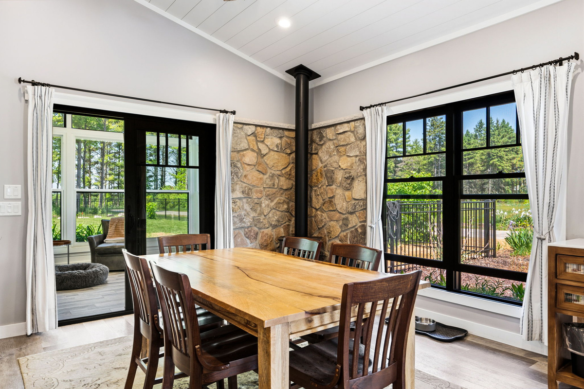 The dining room opens directly to the sun-filled four-season room, blending indoor comfort with the beauty of the surrounding pines.