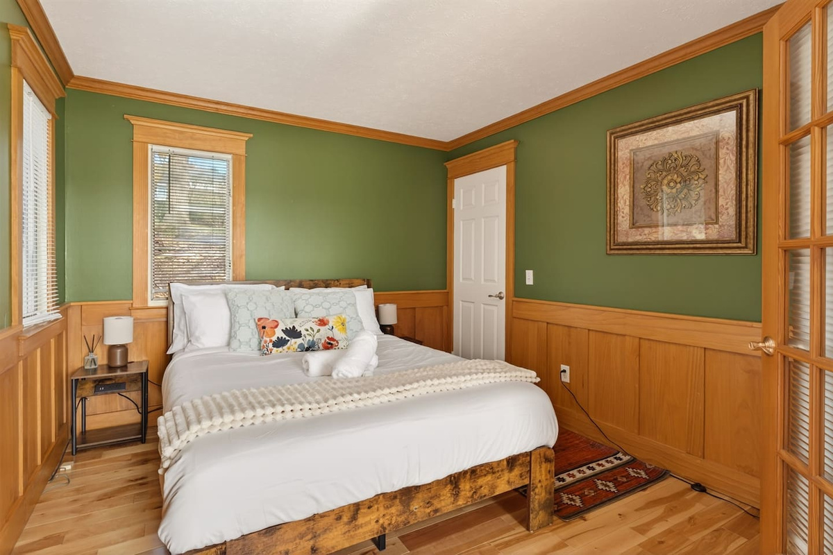 “Escape to the Olive Bedroom—a cozy, nature-inspired retreat with calming green tones and warm wood finishes. Enjoy restful sleep, natural light, and easy access to the living space for a seamless, relaxing stay.”