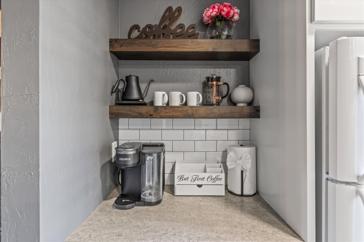 Kitchen corner with refrigerator, coffee station, keurig coffee maker, cabinet storage, and sunny shutters nearby 