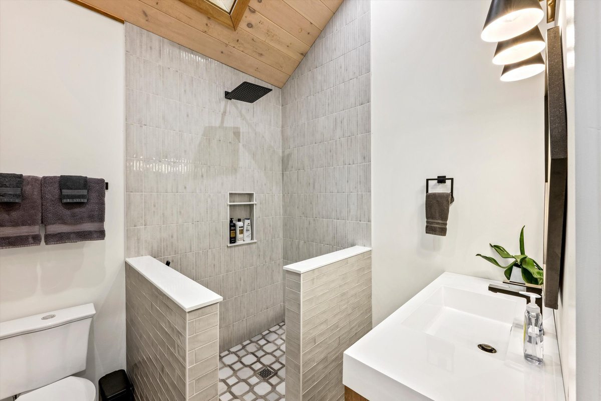Rainfall shower with hand-held ceiling skylight and provided shampoo/conditioner/body wash.