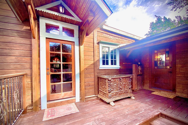 This sheltered porch is the home’s indoor-outdoor crossroads: the glass door leads to the kitchen, while the restored stained-glass door opens to the Bath Annex and two powder rooms—an especially thoughtful flow for groups and approved events.