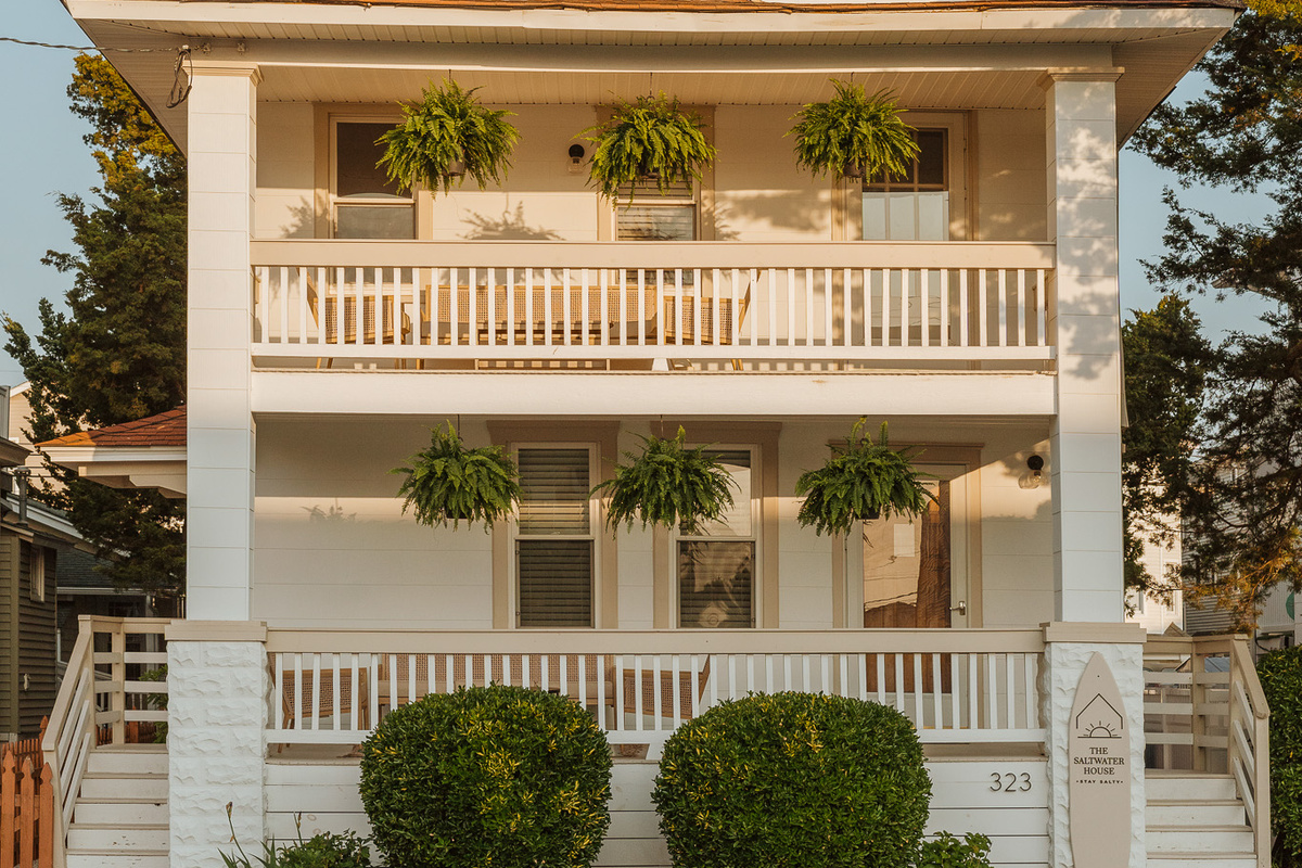 Wide Front Exterior Shot Displaying Multi-Level Covered Porches and Lawn