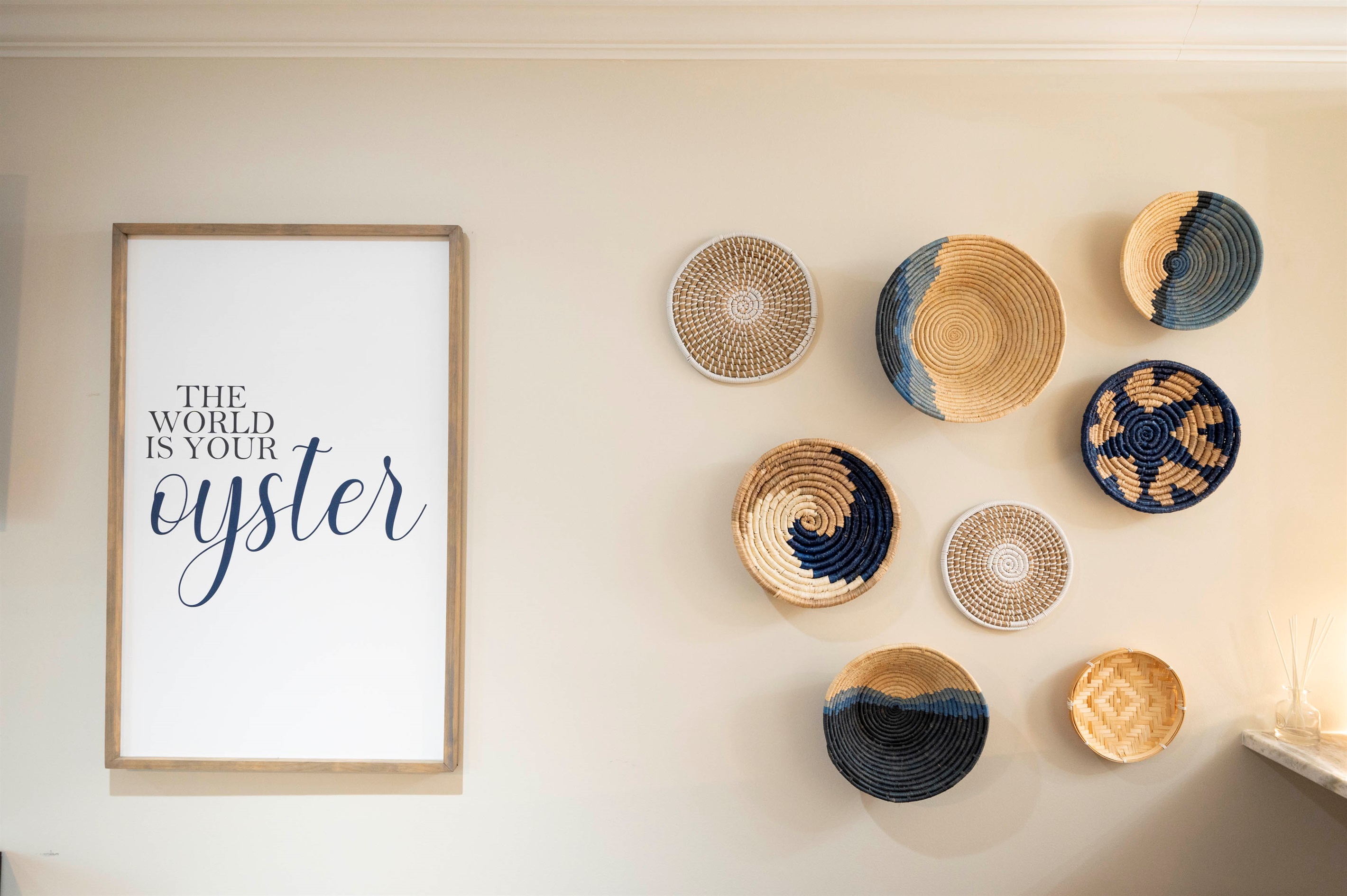 "The world is your oyster" wall art with woven baskets creates an inspiring home decor vibe.