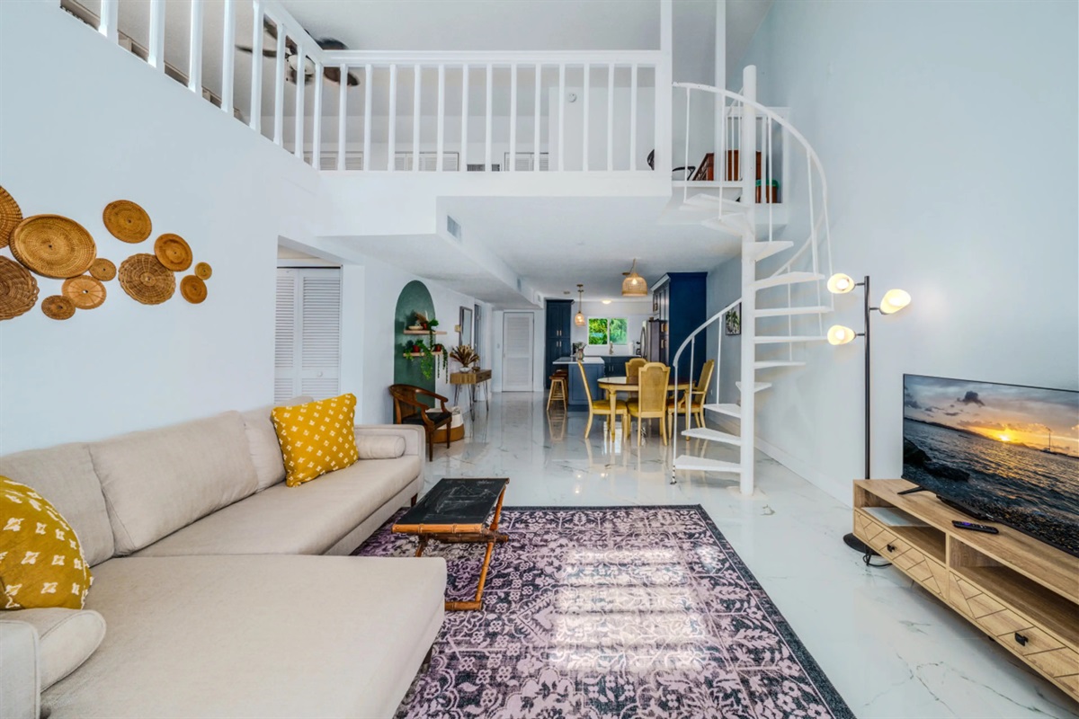 Bright and open living space featuring soaring ceilings and a beautiful spiral staircase leading to the loft.