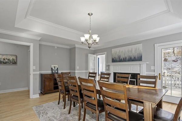 This inviting dining room comfortably seats 10 guests and features a stunning fireplace along with expansive windows that fill the space with natural light.