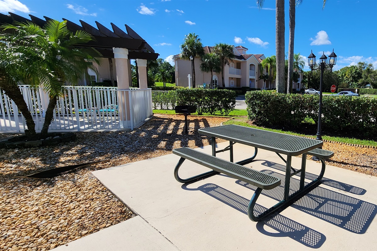 Outdoor picnic area with shaded seating, landscaped surroundings, and convenient access near the pool.