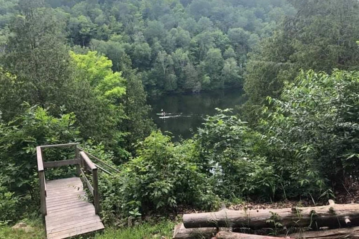 Overlooking Lac MacArthur and paddle boards from lawn area and top of access stairway to dock and lower deck and seating area