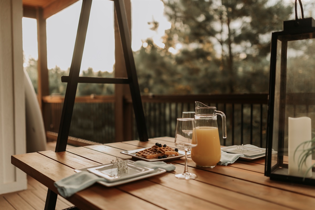 Morning light and forest views set the scene for al fresco dining. Share breakfast, sip juice, and enjoy slow moments together at this inviting outdoor table.