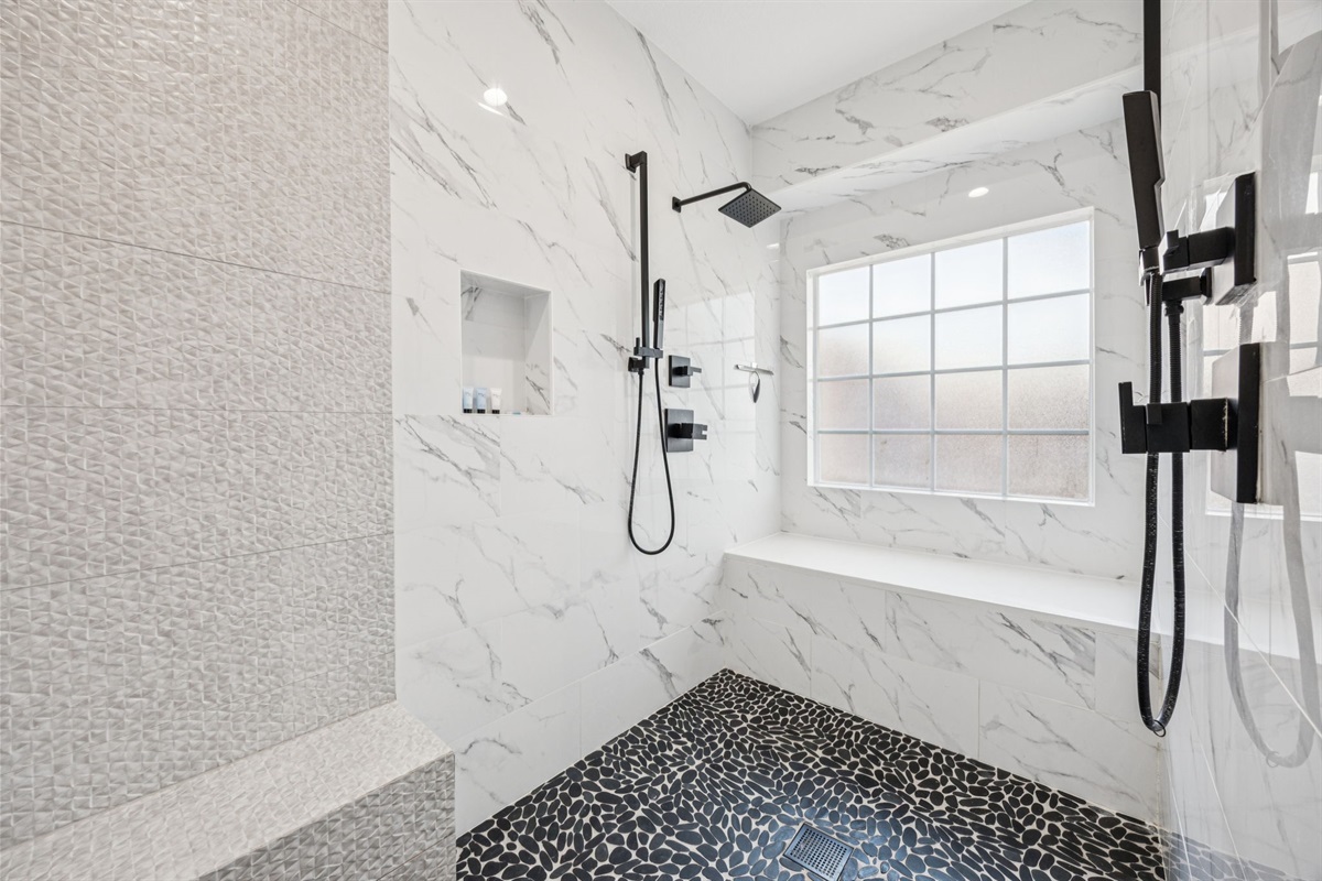 Spa-style bath with dual rain showers and dog-wash bench.