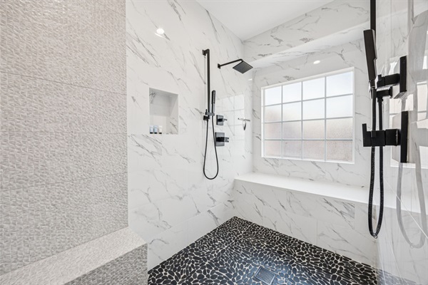 Spa-style bath with dual rain showers and dog-wash bench.