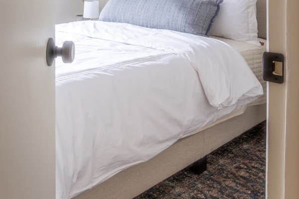 A glimpse of crisp linens and soft layers waiting just through the door.