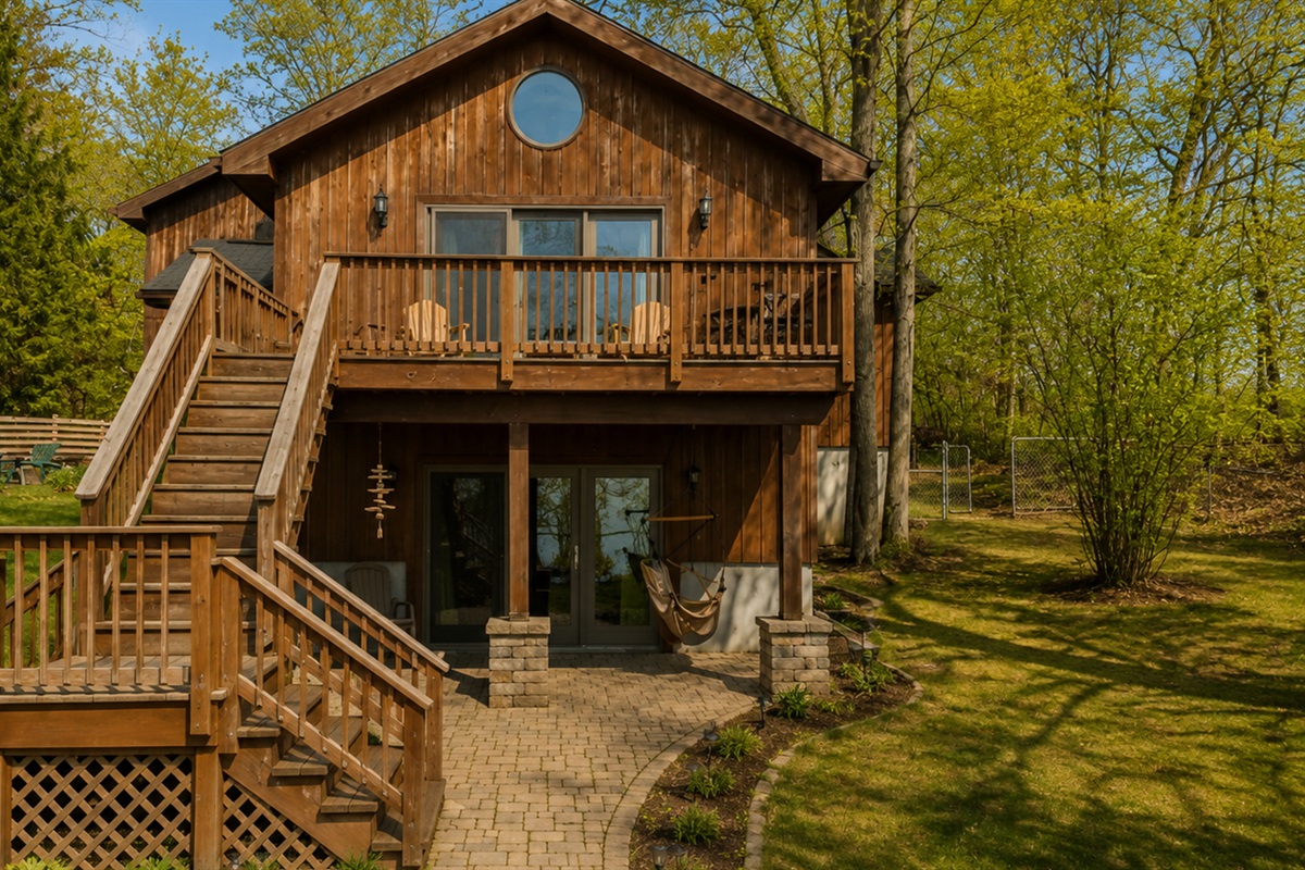 Step into this inviting lakeside cabin featuring a spacious deck, large windows, and cozy hammock, perfect for enjoying nature and lakeside views