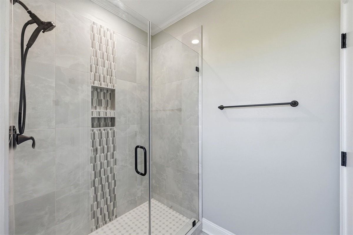 Spa-inspired main-level master bathroom featuring a sleek walk-in shower with elegant tilework and modern finishes