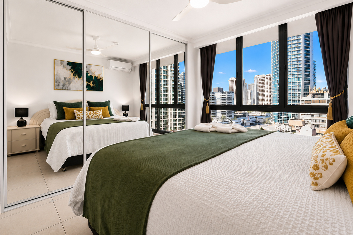 Floor-to-ceiling windows bring the Surfers Paradise skyline into Bedroom 1, adding a high-rise outlook beside the king bed and mirrored wardrobe.