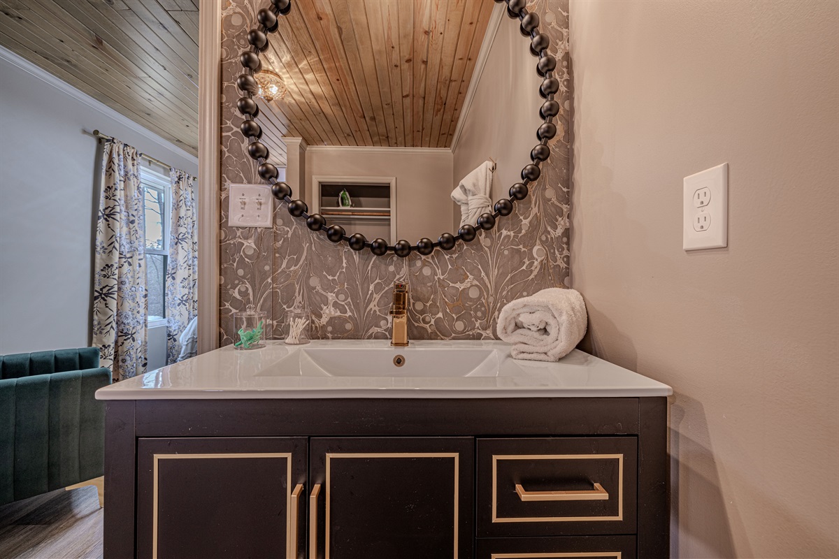 Soft, plush towels and a warm wood-plank ceiling bring a touch of cabin comfort to this beautifully renovated and chic bathroom space.