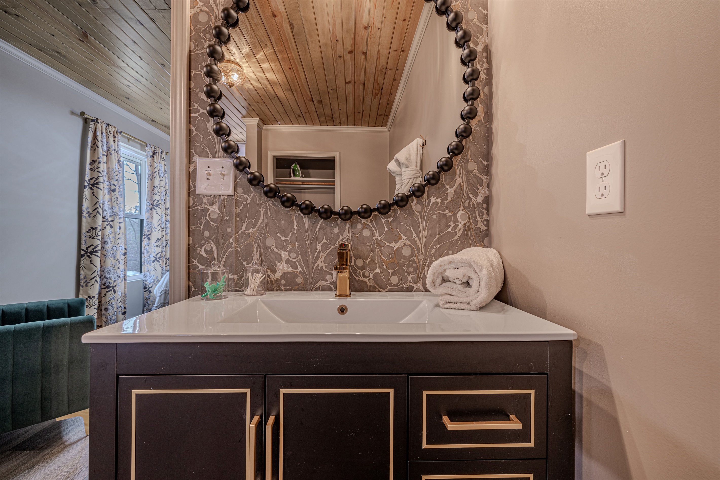 Soft, plush towels and a warm wood-plank ceiling bring a touch of cabin comfort to this beautifully renovated and chic bathroom space.
